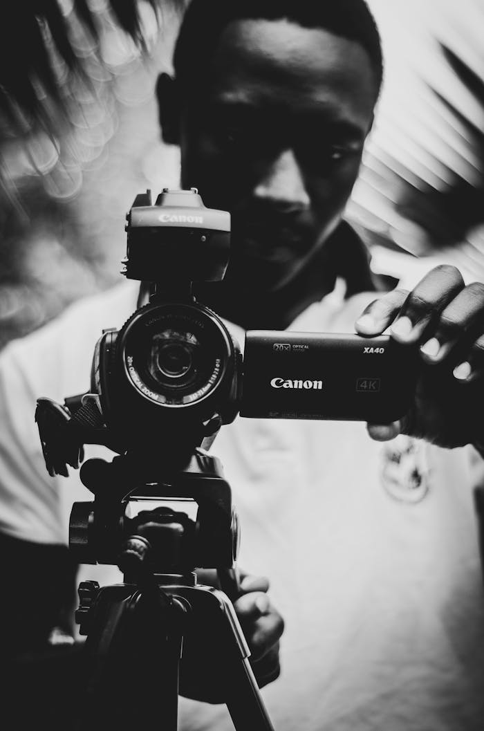 Artistic black and white portrait of a man adjusting camera focus. Captures essence of photography.